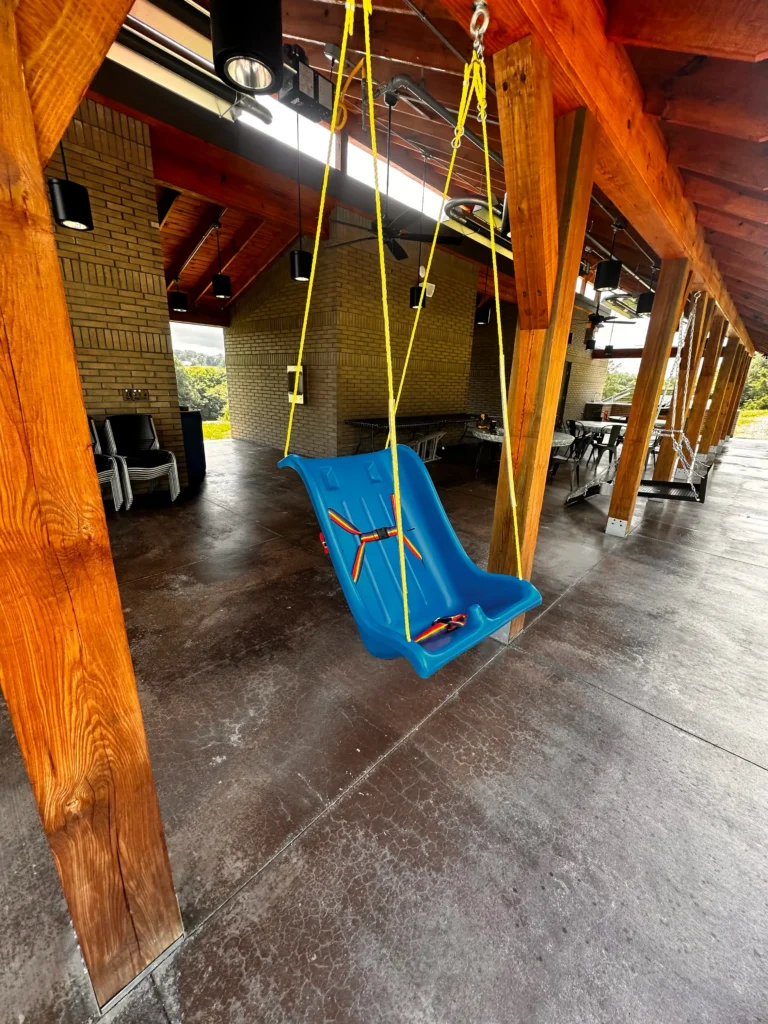 A blue accessible swing hanging on the porch at Trinity Grace Farm