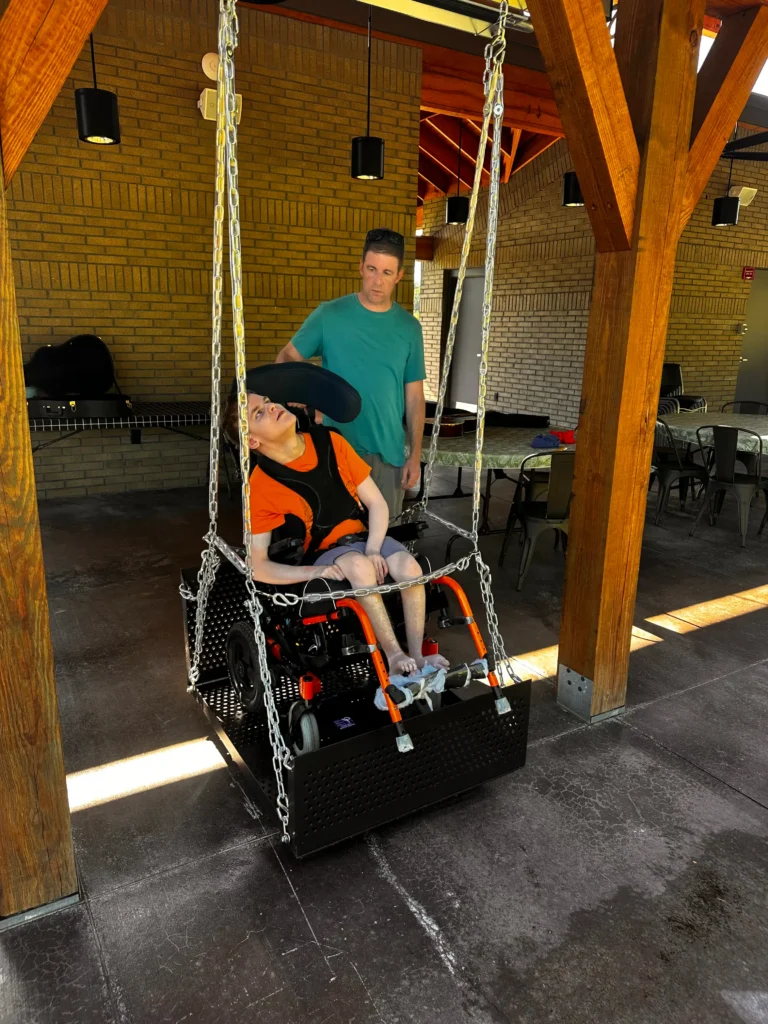 A wheelchair user in an accessible swing on the porch at Trinity Grace Farm