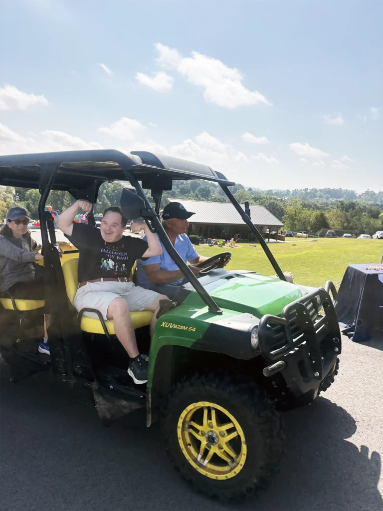 I CAN Resource Fair attendee enjoys a ride on the Farm's green Gator