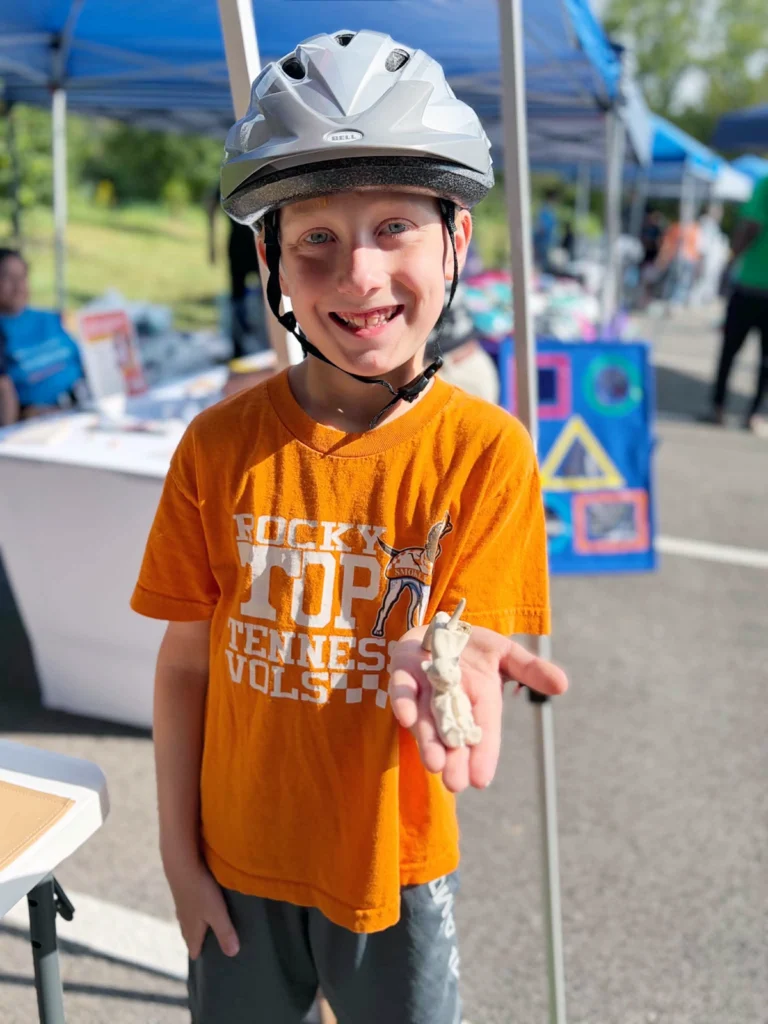 Young boy wearing a bicycle helmet showing an item he received at the I CAN Special Needs Resource Fair